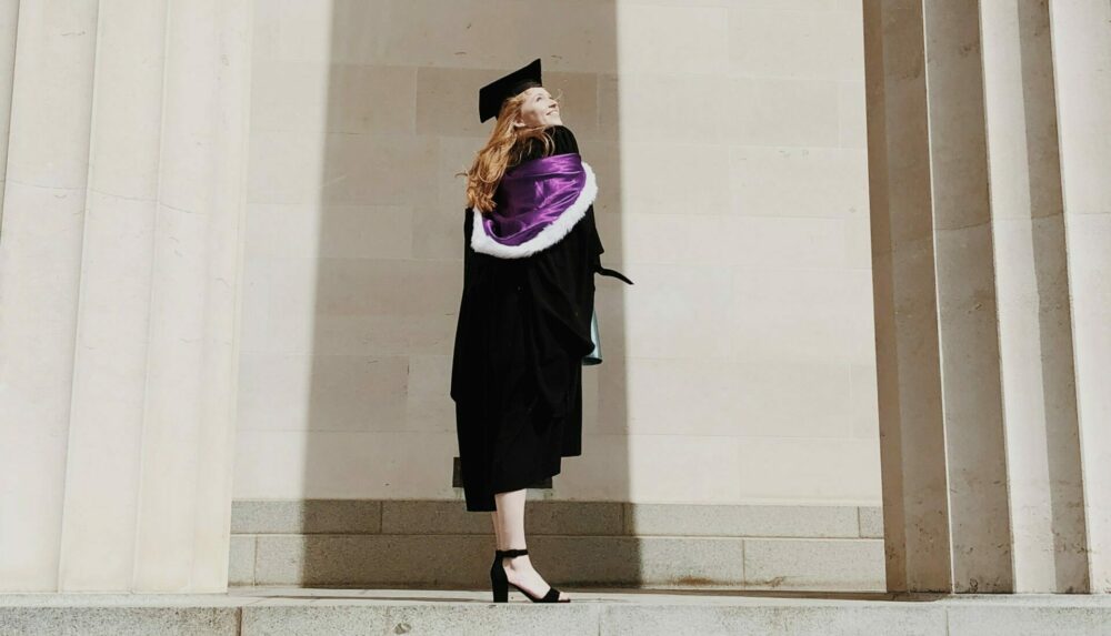 Student in graduation attire outside university